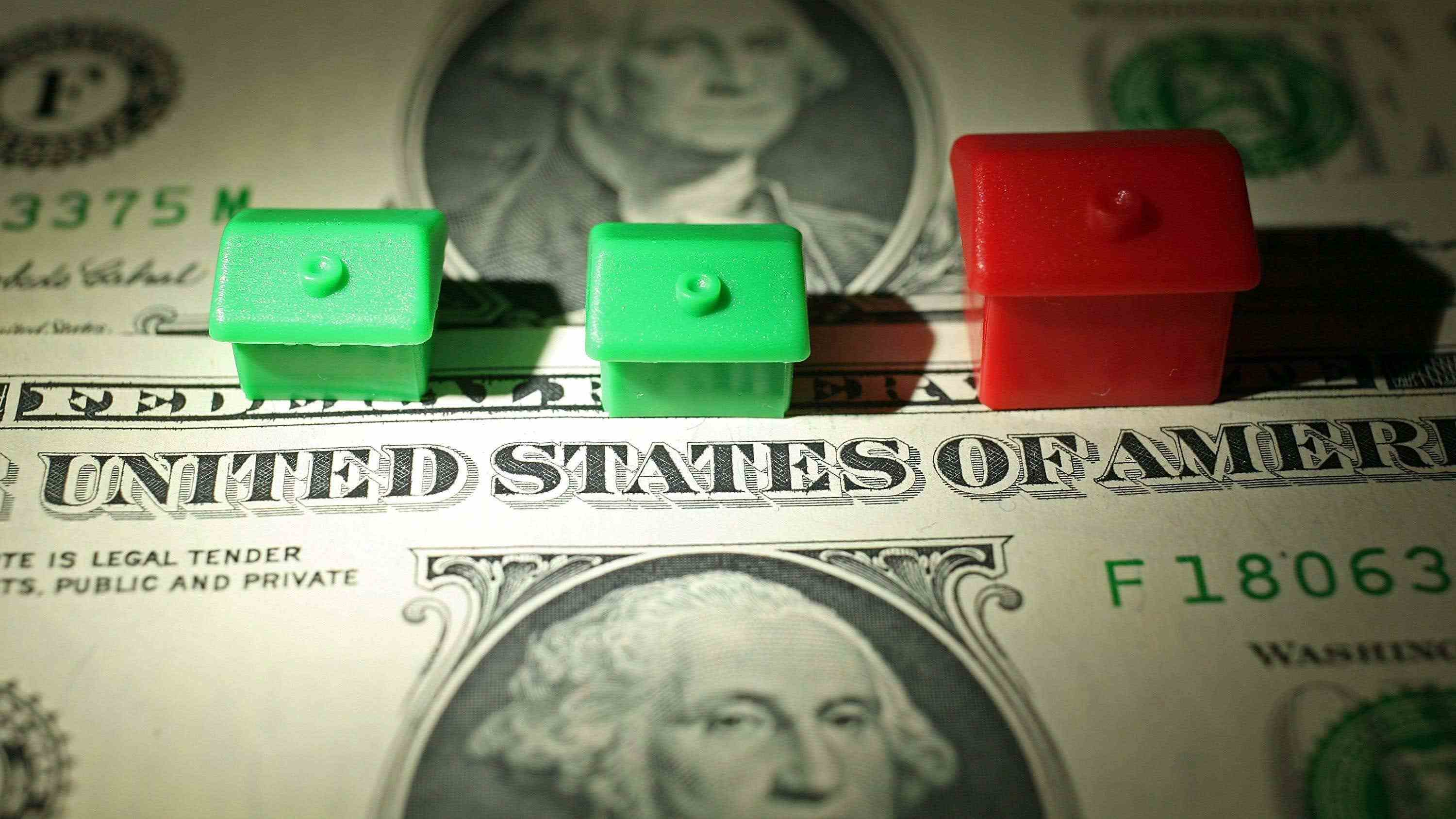İki yeşil Monopoly evi ve iki adet 1 dolarlık banknotun üstünde bir kırmızı ev